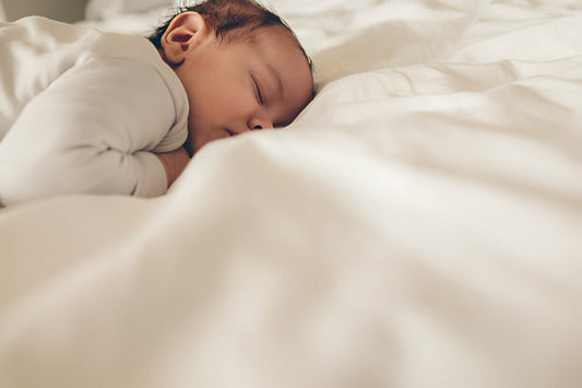 Bebé pequeño durmiendo boca abajo en una cama 
