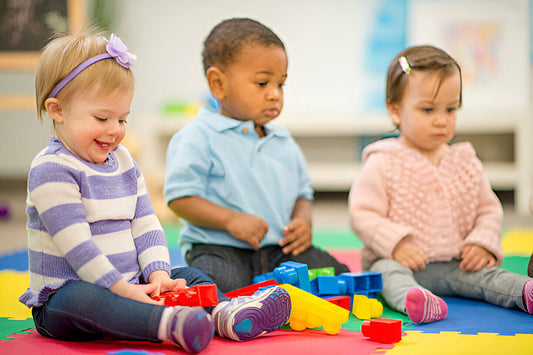 Tres niños sentados en el suelo de colores en el kinder
