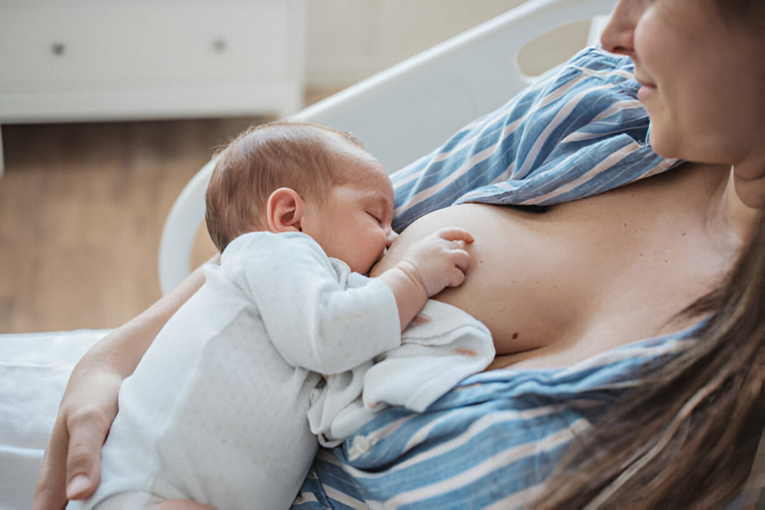 Mamá vestida con una blusa azul amamantando a su bebé